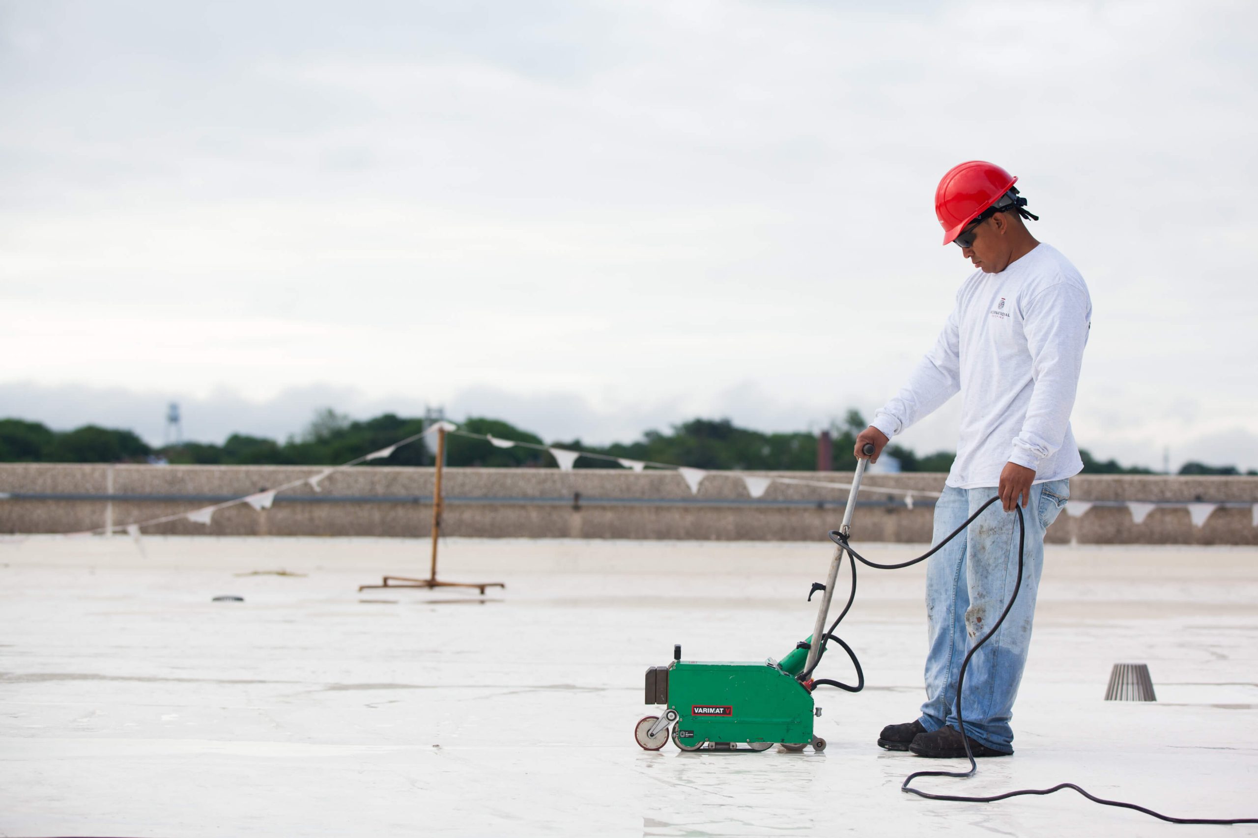 Man on roof with green roofing tool