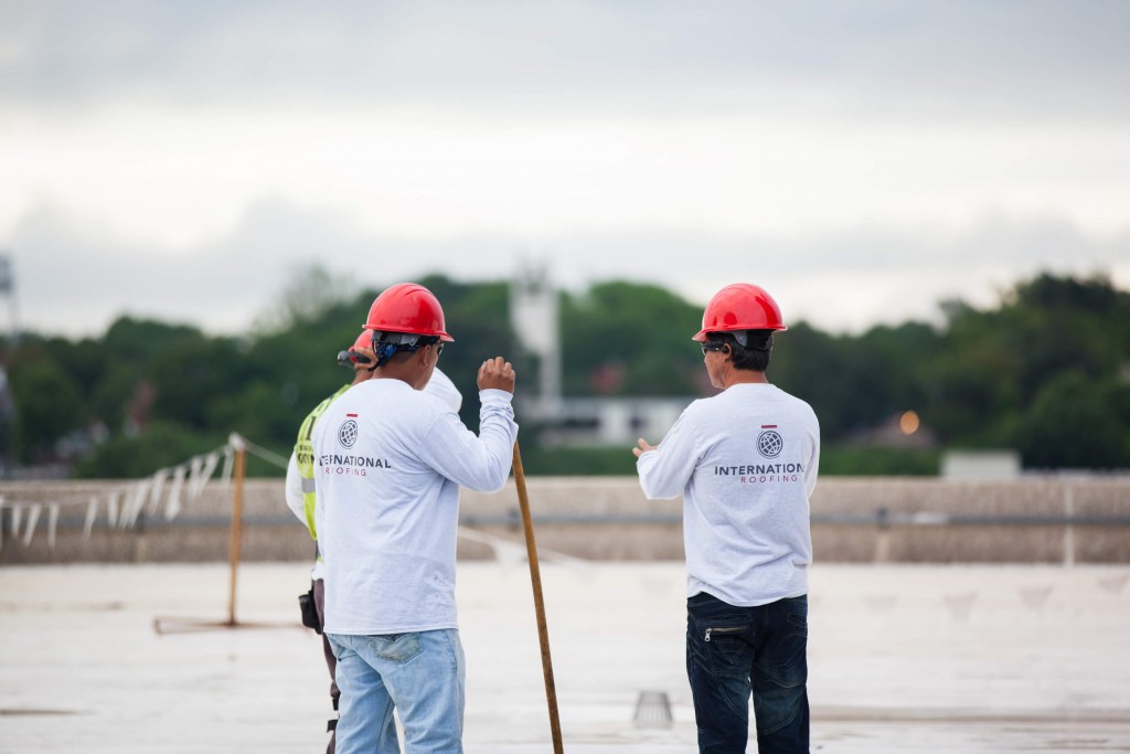 Three men in red hard hats on roof