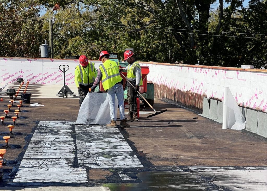 Roofers pulling up waterproofing material